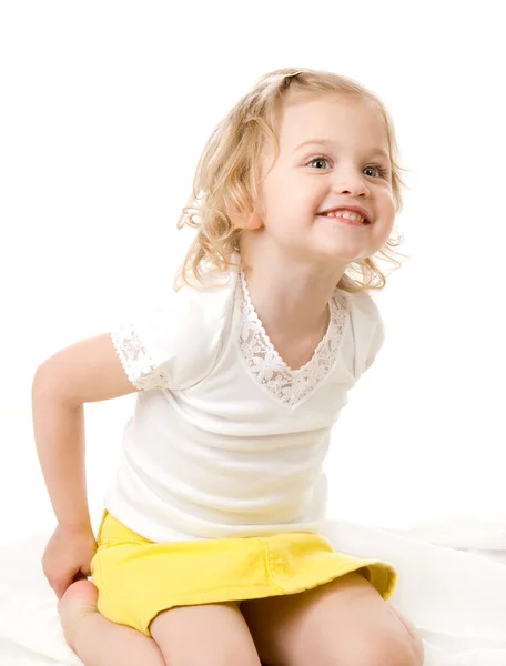 Niña feliz vistiendo una falda amarilla sentada sobre fondo blanco — Foto de Stock