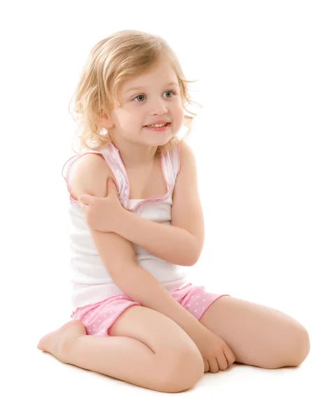 Beyaz zemin üzerine oturan bir pijama giymiş küçük sarışın kız — Stok fotoğraf