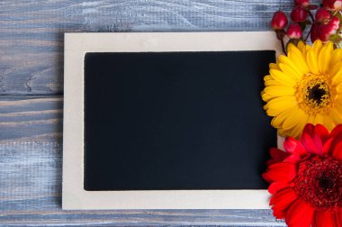 Siyah tahta, sarı ve kırmızı çiçekler eski püskü ahşap arka planda. Metin için alanı kopyala.