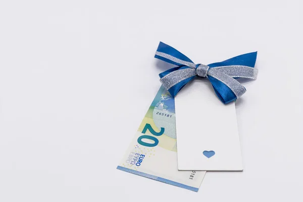 20 avroluk kağıt bir banknot ve beyaz arka planda mavi fiyonklu bir hediye etiketi. Kopyalamak için boş yer. Hediye konsepti, nakit prim, ödül.