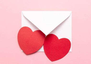 Pembe arka planda iki kırmızı kalbi olan beyaz bir zarf. Bir aşk mektubu. Sevgililer Günü 'nü, Anneler Günü' nü, Kadınlar Günü 'nü kutlarım. Bir aşk ilanı