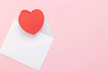 Pembe arka planda büyük kırmızı bir kalbi olan beyaz bir zarf. Kalpli bir aşk mektubu. Sevgililer Günü 'nde, Anneler Günü' nde, Kadınlar Günü 'nde, aşk mektubunda.