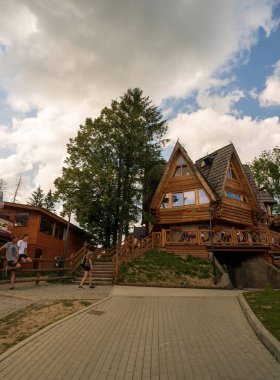 Zakopane, Polonya - 13 Ağustos 2021: Gubalowka 'da dramatik bulutlara karşı bir ağacın yanında şekilli bir ev veya restoran