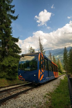 Zakopane, Polonya - 13 Ağustos 2021: Temel demiryolu tramvayı Gubalowka 'ya doğru hareket ediyor Avrupa' da dağ ve dramatik bulutlara karşı