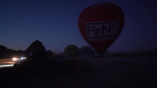 カッパドキア トルコ 9月14 2021 夜の飛行の直前に人々の束でそれに火を吹くことによってヘリウムガスで熱気球を充填するプロセス 気球に乗る前に2台のスーパーカー — ストック動画