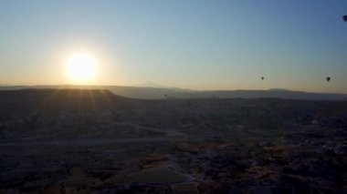 Kapadokya, Türkiye: Kayalık tepe arazisi ve gün doğumu ve gün batımına karşı Goreme 'in doğal parkında, tarihi ve manzarasında, pek çok sıcak hava balonunun insansız hava görüntüsü