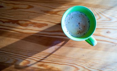 Köpüklü kapuçino ya da sütlü latte, ahşap desenli arka planda kapalı kahve fincanı manzaralı yakın plan. Kafe ve bar, barista sanat konsepti. Bir keseden kahve.
