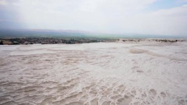 Pan shot of White travertine terrace formations, pool with clear hot water from thermal springs in Pamukkale, Denizli Province in southwestern Turkey. Pamukkale is most visited turkish travel attraction