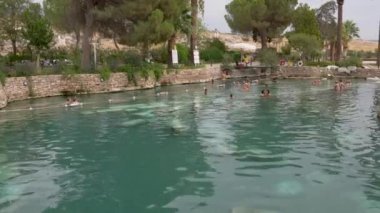 Pamukkale, Turkey - September 14, 2021: People swimming in ancient thermal pool of queen Cleopatra in a Hierapolis, Pamukkale resort