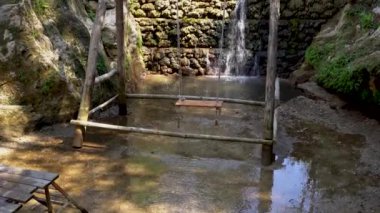 Exotic location of a swing above water stream against small man made waterfall in the forest , adventure concept tropical landscape
