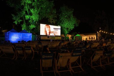 Krakow, Poland - August 19, 2022: An open cinema or movie projecting documentary for public at night with several people watching
