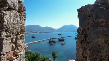 Türkiye 'de Alanya limanının hava görüntüsünü deniz ve dağlara karşı yelkenli gemilerle yakınlaştır