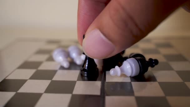 敗北した兵士に囲まれたチェスボードにチェスの王の姿を置く手 勝利の概念 — ストック動画