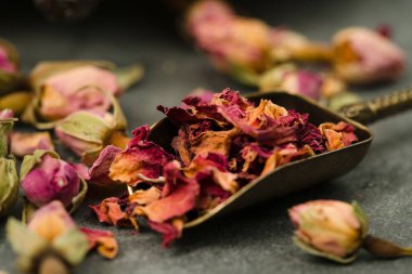 Bir kaşıkta kurumuş gül yaprakları ve tomurcuklar.