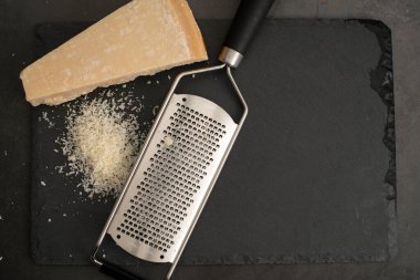 Koyu arkaplanda parmesan peyniri ve peynir rendesi