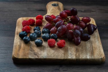 Tahtada taze yaban mersini, ahududu ve üzüm.