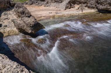 Bir adam nehrin kayalıklarında yürüyor..