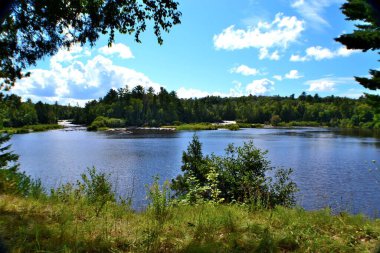 Michigan 'ın Yukarı Yarımadası' ndaki Tahquamenon Nehri 'nin güzel şelaleleri Cennet kasabasında. Gölün her iki tarafında da şelaleler görmek için sağa ve sola bakın. Güzel mavi bulutlu gökyüzü bir ağustos günü. 