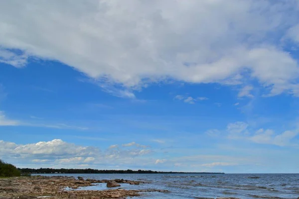 背景に大きなふわふわの雲がある美しい青空を背景に 石灰岩の棚ビーチエリアの上の空 メノミニー ミシガン ジョン ヘンス公園のグリーン湾のミシガン湖 水と土地の間に緑の水平線と春 — ストック写真