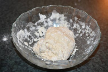 Pizza hamuru yapmanın ilk aşamalarının detaylarına dikkatle odaklanın. Kabarık yüzeyli bir cam kase içinde tezgahın üzerinde dinleniyor. Pizza Hamuru yoğurmaya hazır.