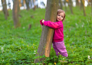 küçük kız bir ağaç gövdesi sarılma