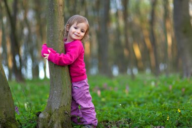 küçük kız bir ağaç gövdesi sarılma