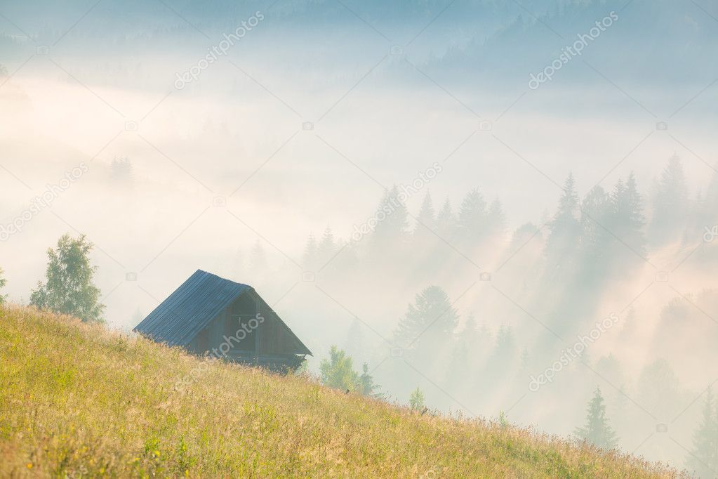 Foggy landscape with an old barn in the mountains