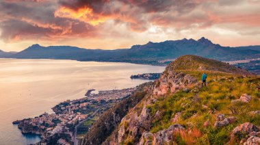Turistler Akdeniz kıyısındaki yüksek kayalıklarda gün doğumuna hayrandı. Bagheria şehri ve ulusal park Orientata Pizzo Cane, Pizzo Trigna e Grotta Mazzamuto, Sicilya, İtalya. 