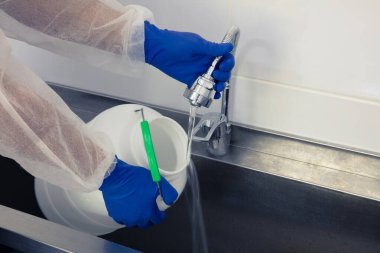 Carpathian köyünde küçük bir aile peynir fabrikası. Süt resepsiyonu için konteynır temizleme.