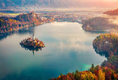 Maria 'nın Hipotezi Kilisesi' nin puslu sabah manzarası. Bled Gölü 'nde çarpıcı bir gün doğumu. Büyük sonbahar manzarası Julian Alps, Slovenya, Avrupa. Seyahat konsepti arka planı.