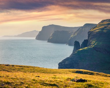 Atlantik Okyanusu kıyısındaki yüksek kayalıklar. Faroe Adaları, Danimarka, Avrupa 'nın muhteşem yaz manzarası. Heyecan verici bir sabah deniz manzarası. Doğa konseptinin güzelliği