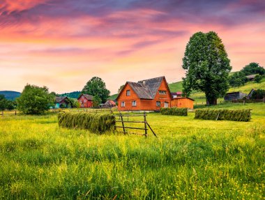 Yasinya köyünde, Ukrayna, Avrupa 'da ahşap evleri olan muhteşem bir yaz gündoğumu. Karpatlar 'da Haymaking. Kırsal kesimin güzel bir sabah manzarası. Seyahat konsepti arka planı.