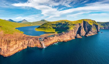 Bosdalafossur şelalesinin uçan insansız hava aracının panoramik görüntüsü doğrudan okyanusa düşüyor. Sorvagsvatn Gölü, Vagar, Faroe Adaları, Danimarka, Avrupa 'nın etkileyici yaz sahnesi.
