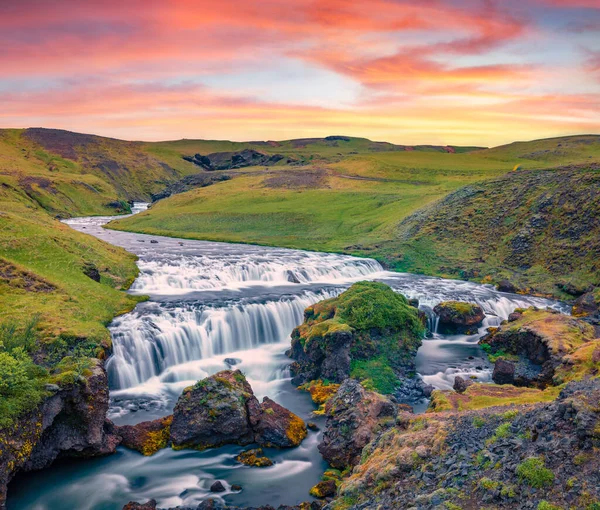 Skoga nehrinde fantastik bir şelale. Skogafoss şelalesinin eteklerinde renkli bir yaz gündoğumu. İzlanda, Avrupa 'nın resimli sabah manzarası. Güzel yaz manzarası