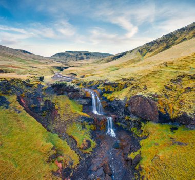Uçan İHA 'nın görüntüsü. Rauda Nehri 'ndeki isimsiz şelalenin görkemli sabah manzarası. Haziran 'da İzlanda' nın güney kıyısında resim gibi yeşil tepeler. Doğa konseptinin güzelliği.
