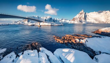 Hamnoy Köprüsü, Lofoten Adaları 'ndaki Hamnoy köyünün karlı kış manzarası. Taze kar, Norveç denizinin kıyısındaki taşları ve dağ zirvelerini kaplıyor. Norveç, Avrupa 'nın Sabah Sahnesi. 