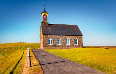 Sarı çiçeklerin arasında Hvalsneskirkja Kilisesi 'nin renkli sabah manzarası. İzlanda 'nın büyüleyici yaz manzarası, Keflavk' ın yeri. Seyahat konsepti arka planı
