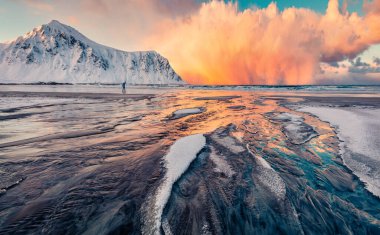 Norveç, Avrupa 'daki Lofoten Adaları' nın nefes kesici kış manzarası. Fırtına bulutları güneşin ilk ışıklarını aydınlattı. Popüler turizm merkezinin sabah manzarası - Skagsanden plajı, Flakstadoya adası.