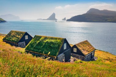 Arka planda tipik çimenlik evler ve Tindholmur kayalıkları olan Bour köyünün nefes kesici yaz manzarası. Vagar Adası, Faroe, Danimarka Krallığı, Avrupa 'nın büyüleyici sabah manzarası. 