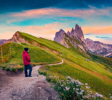Yürüyüşçü, Furchetta zirvesinin olduğu fantastik günbatımına hayran. Funes Valley 'in muhteşem yaz sahnesi. Puez Odle Ulusal Parkı, Dolomiti Alpleri, Güney Tyrol, İtalya ve Avrupa 'da heyecanlı bir akşam..