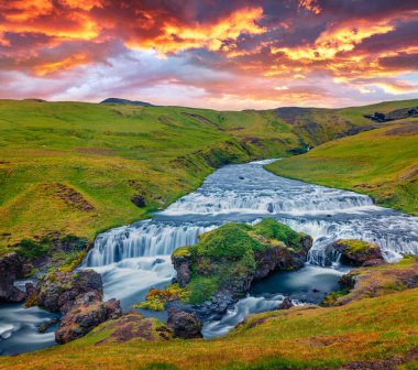 Güzel İzlanda manzarası. Skoga nehrinde görkemli bir şelale. Skogafoss şelalesinin eteklerinde muhteşem bir yaz gündoğumu. İzlanda, Avrupa 'nın resimli sabah sahnesi. 