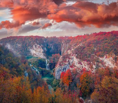 Plitvice Ulusal Parkı, Hırvatistan ve Avrupa kanyonundaki kırmızı tepeler. Plitvice 'deki saf su şelalesinin dramatik sabah manzarası. Dağ ormanlarında muhteşem sonbahar gündoğumu. Doğa konseptinin güzelliği.