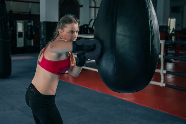 Woman boxing with punching bag in garage gym