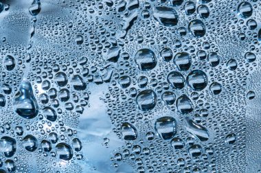 Su damlaları mavi arkaplanda. Cam yüzeydeki su damlacıkları.