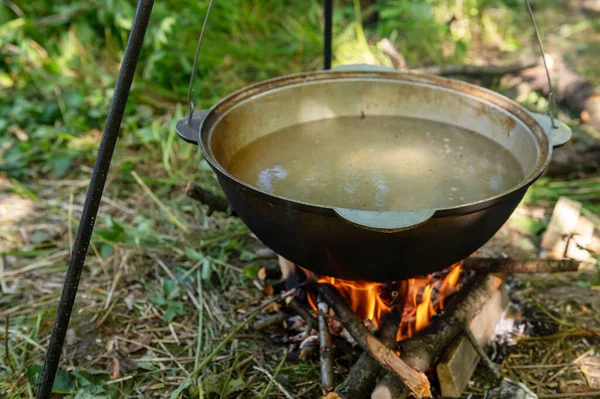 Yangında kazan var. Yaz günü vahşi bir kamp alanında kamp ateşinde yemek pişirmek. Dinlenme kavramı
