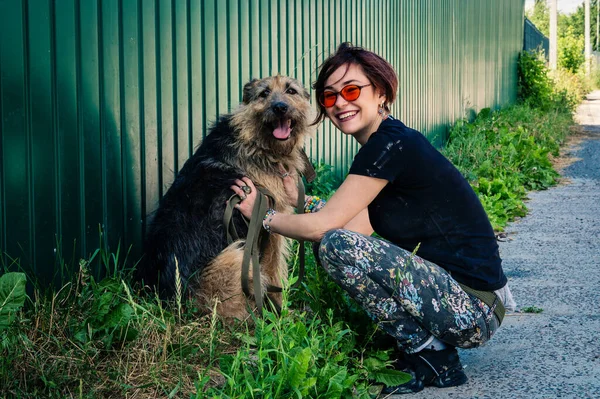 Barınaktaki köpek. Hayvan barınağı gönüllüsü köpekleri besliyor. Kafeste yalnız köpekler ve neşeli bir gönüllü kadın.