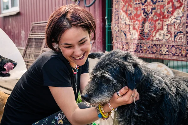 Dog at the shelter. Animal shelter volunteer takes care of dogs. Lonely dogs in cage with cheerful woman volunteer.