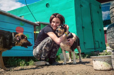 Hayvan barınağı gönüllüsü köpeklerle ilgileniyor. Kafesteki yalnız köpekler ve neşeli kadın gönüllü. Barınaktaki köpek. 