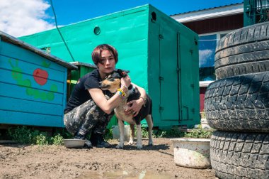 RIVNE, UKRAINE - JUNE 21, 2022. Lonely dogs in cage with volunteer. Animal shelter volunteer takes care of dogs. Dogs at the shelter. 