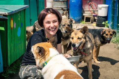 RIVNE, UKRAINE - JUNE 21, 2022. Lonely dogs in cage with volunteer. Animal shelter volunteer takes care of dogs. Dogs at the shelter. 